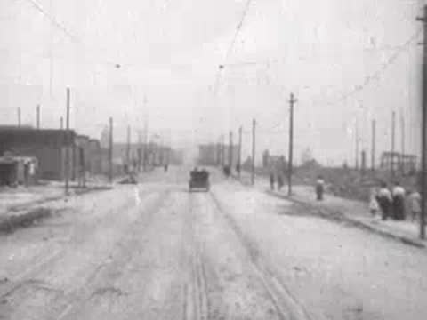 distant horse-drawn carriage driving down city road, historical footage