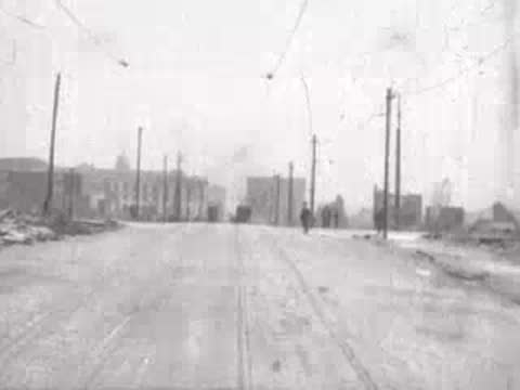 wide damaged street with distant figures, historical footage
