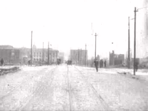 pedestrian walking beside wide ruined street, historical footage