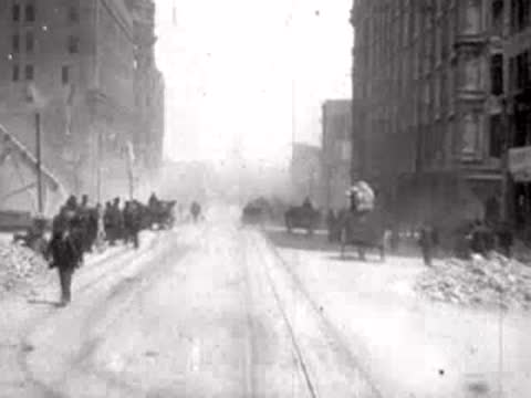 pedestrians and carriages on street between buildings, historical footage