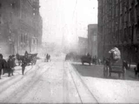 Street view after San Francisco earthquake, horse-drawn carts, rubble, pedestrians.