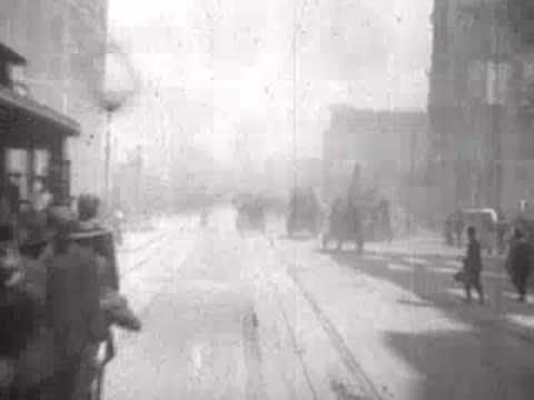 Street view after San Francisco earthquake, passing cable car, pedestrians, rubble.