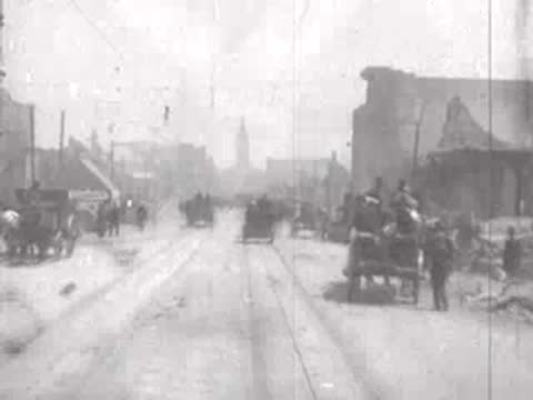 Street view after San Francisco earthquake, horse carriages, rubble, pedestrians.