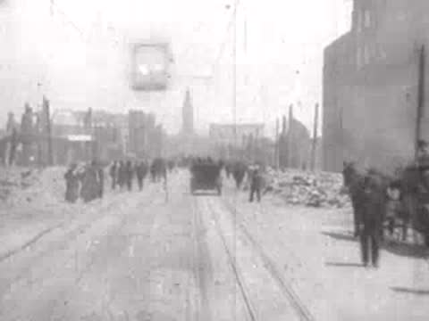 Street view after San Francisco earthquake, horse carriages, rubble, pedestrians.