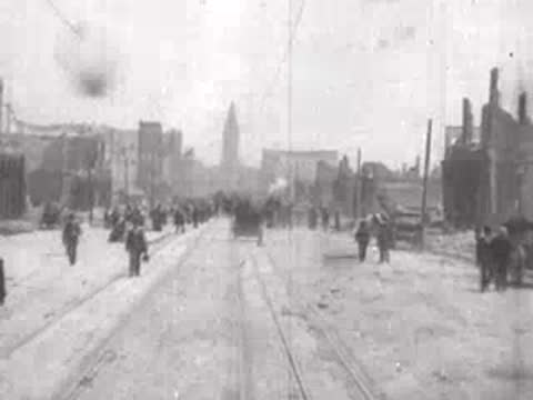 Street view after San Francisco earthquake, pedestrians, horse-drawn carts, rubble.