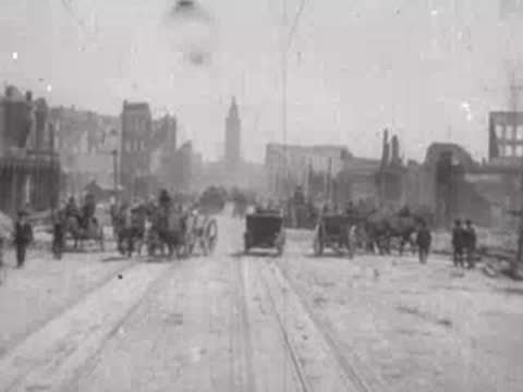 Street view after San Francisco earthquake, horse-drawn carts, pedestrians, debris.