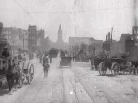 Street view after San Francisco earthquake, horse carriages, pedestrian carrying bag, rubble.