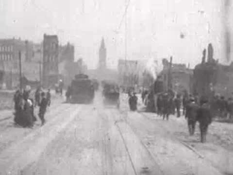 Street view after San Francisco earthquake, approaching cable car, pedestrians, debris.