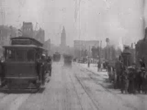 Street view after San Francisco earthquake, passing cable car, pedestrians, debris.
