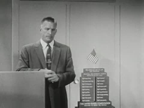Man standing behind podium with stacked display behind him