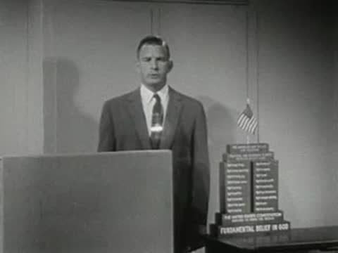 Man speaking behind podium with stacked display behind him