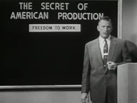 Man turning to point at blackboard with text 'THE SECRET OF AMERICAN PRODUCTION'