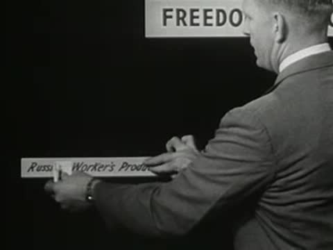 Man attaching sign 'Russian Worker's Production' to a black board