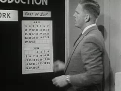 Man adds a label to a calendar chart on a board, 1950s