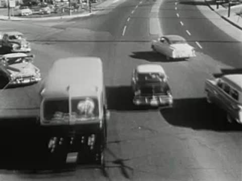 overhead tracking shot of vintage cars driving on a city street