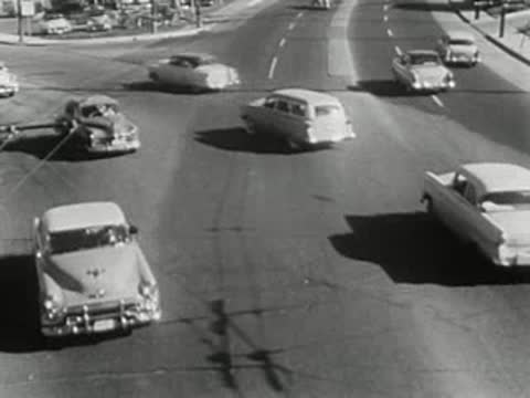 aerial tracking view of mid-century automobiles driving on a multi-lane highway