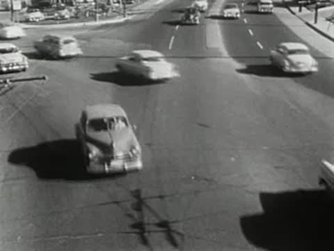 overhead tracking shot of classic cars traveling along a city avenue
