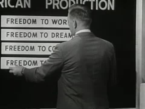 man in suit turning to add text blocks to a board on set