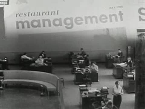 wide view of workers at desks in a large office with magazine text overlay