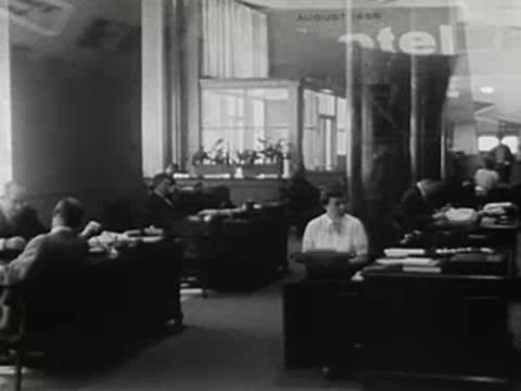 medium shot of office workers typing at desks with superimposed window and text graphics