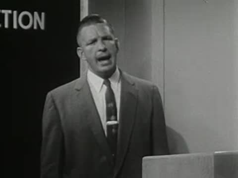 medium close-up of a man in a suit speaking behind a podium