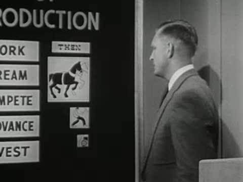 man gesturing toward a board featuring an icon and text on set