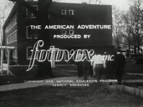 Production credits overlay a shot of people walking toward a building exterior.