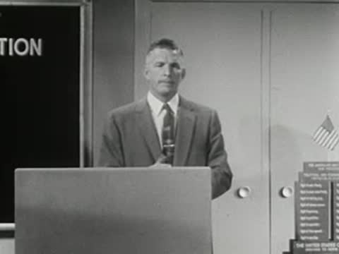Man standing at podium giving a speech in a studio setting