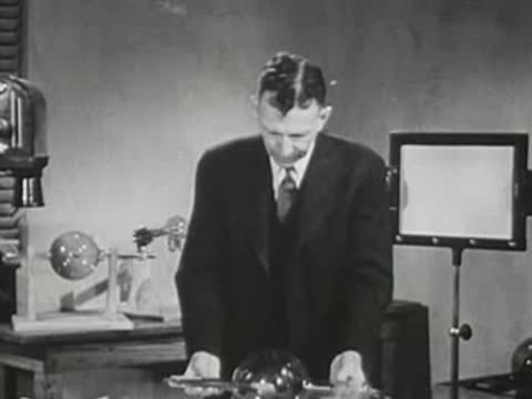 Presenter at a table picking up a specialized glass vacuum tube.