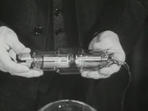 Close-up of hands holding and rotating a small tubular electronic apparatus.