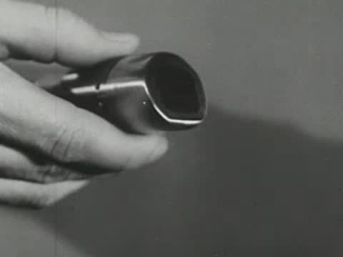 Close-up of human hands holding and rotating a metallic anode from an X-ray tube.