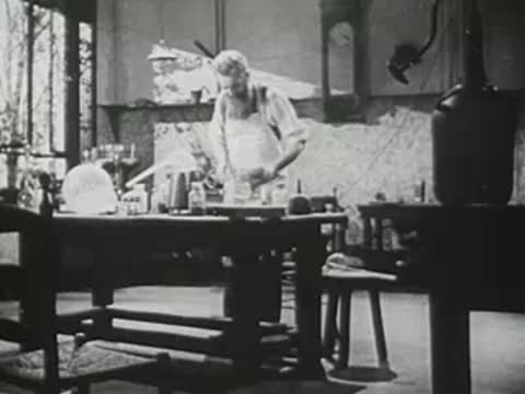 Bearded man in historical costume working in a period laboratory.