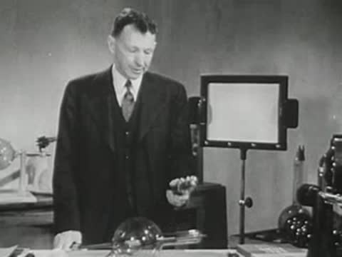 Lecturer holding spherical objects stands by the laboratory workbench.