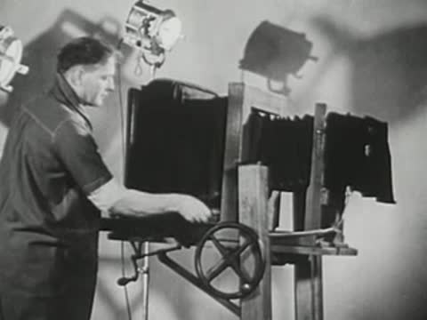 Technician operates industrial X-ray inspection machinery with a hand wheel.