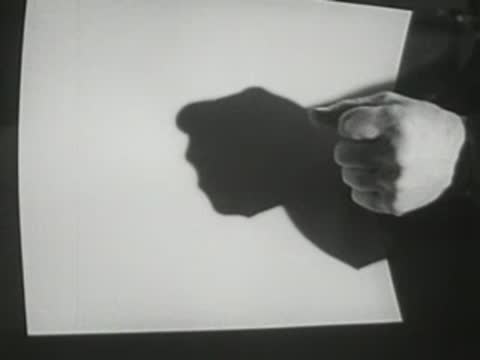 Shadow puppet demonstration of a hand casting shadows on an illuminated screen.