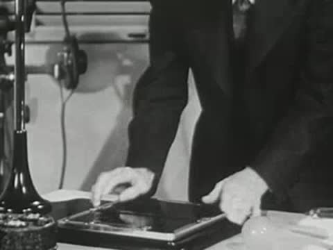 Man places a sheet of photographic film in a holder, 1940s scientific demonstration.