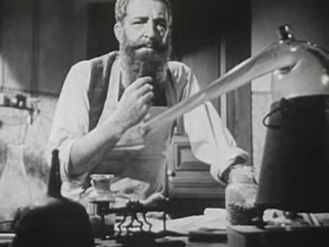 Close-up of bearded man working with glass apparatus in laboratory.