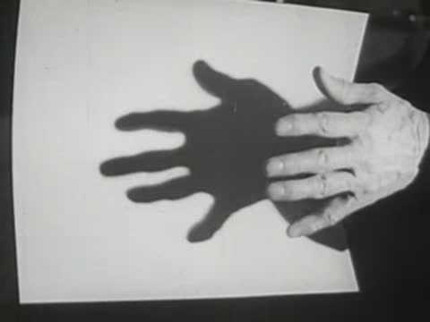 Shadow of a hand cast onto a white sheet, 1940s style.