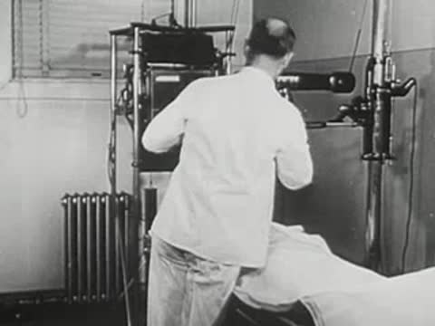 Medical professional preparing an X-ray machine over a patient.