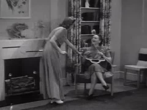 Woman sitting in a chair as another woman enters living room, interior