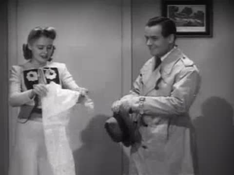 Couple removing raincoats in a hallway, 1940s home interior