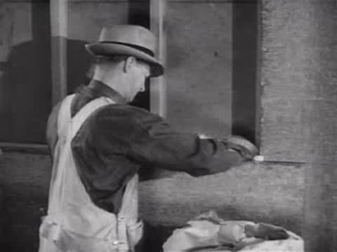 Worker in overalls applying strips of material to a wall, workshop