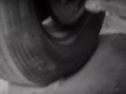 A car tire driving slowly over a large piece of heavy fabric.