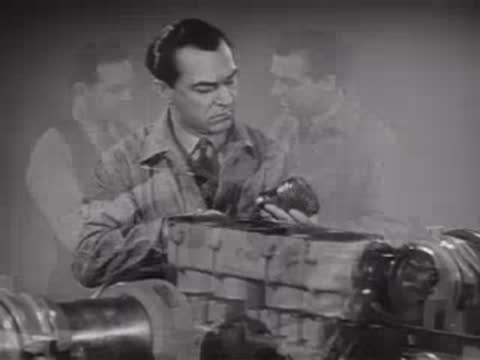 Two men examining and working on machinery components in a workshop.