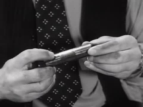 Close-up of a man's hands inspecting a small cylindrical metal part.
