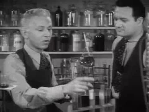 Two researchers in a laboratory working with test tubes and glassware.