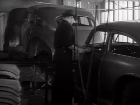 A worker inspecting the interior of a car chassis in an assembly line.