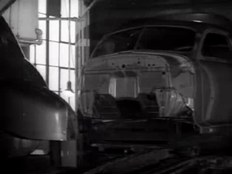 The front body of a car moving along an industrial assembly line.