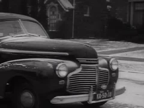 Front view of a shiny 1940s sedan parked on a city street.