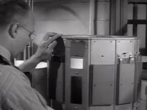 A technician inserting test panels into slots on a rotary testing machine.